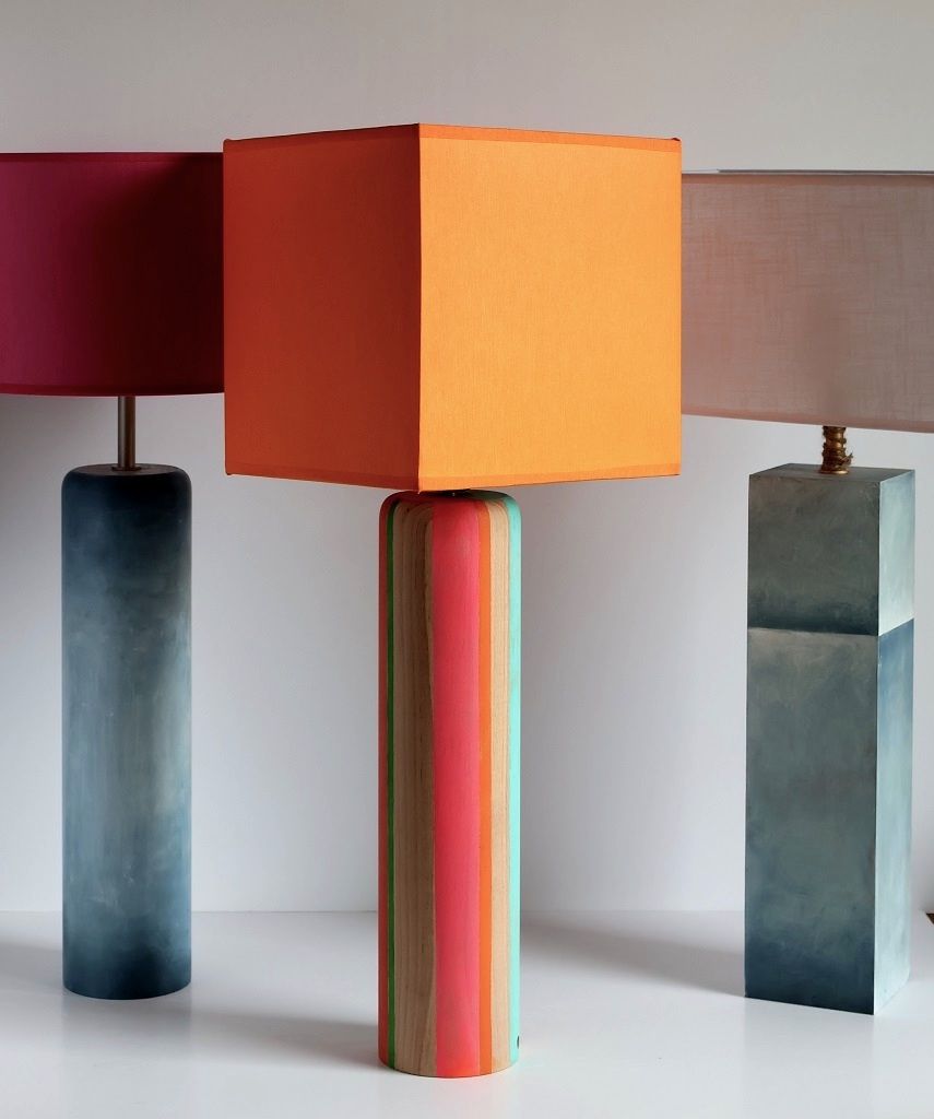 Tres lámparas de diferentes colores están alineadas sobre una mesa.