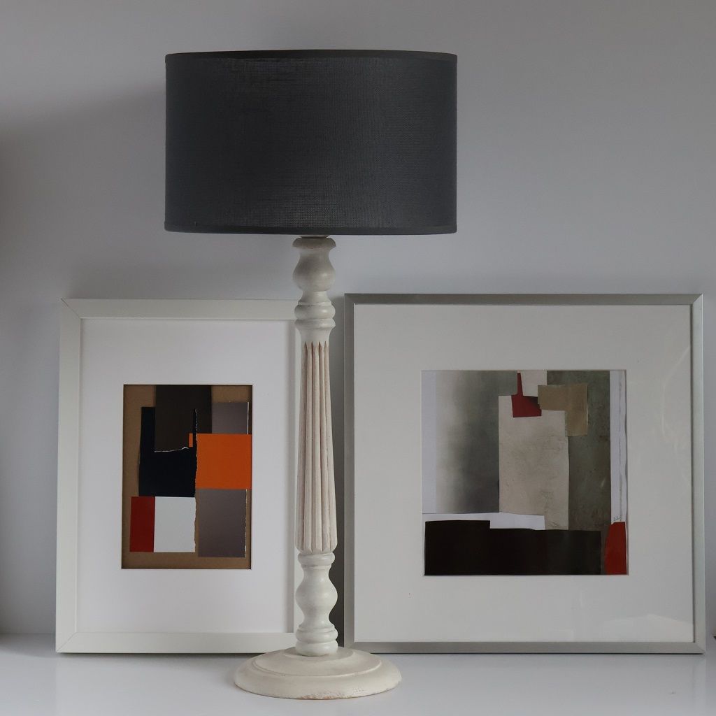 Una lámpara y dos cuadros enmarcados sobre una mesa.