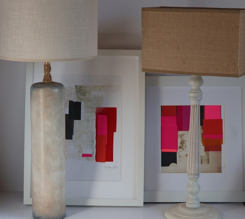 Una lámpara está sobre una mesa al lado de dos cuadros enmarcados.