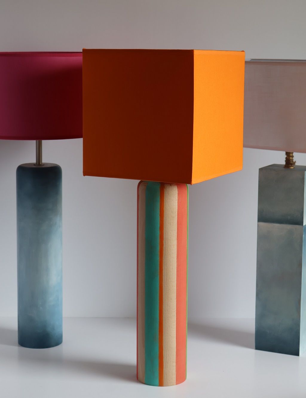 Tres lámparas con diferentes pantallas están alineadas sobre una mesa.