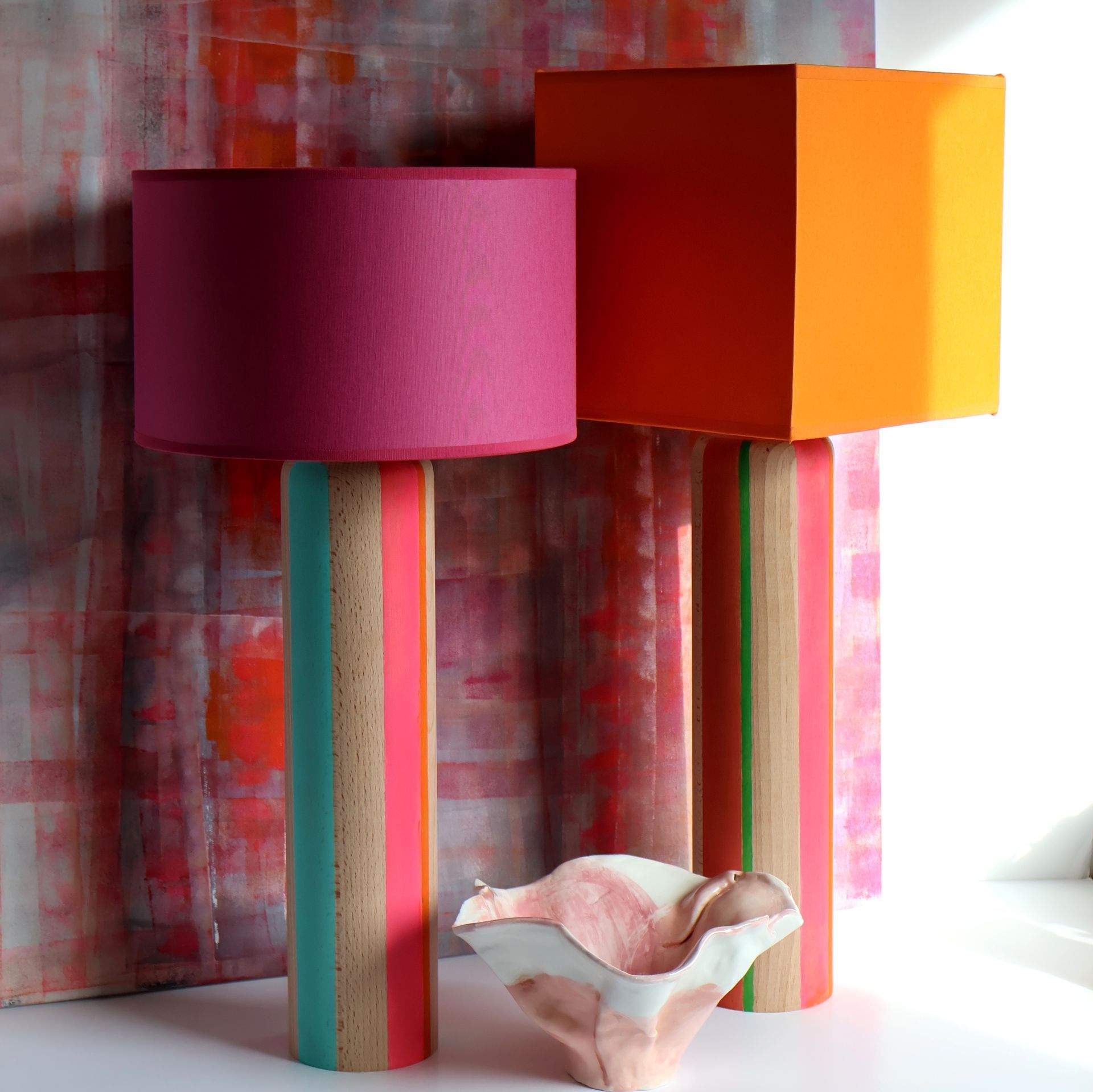 Tres lámparas de colores están sobre una mesa delante de un cuadro.