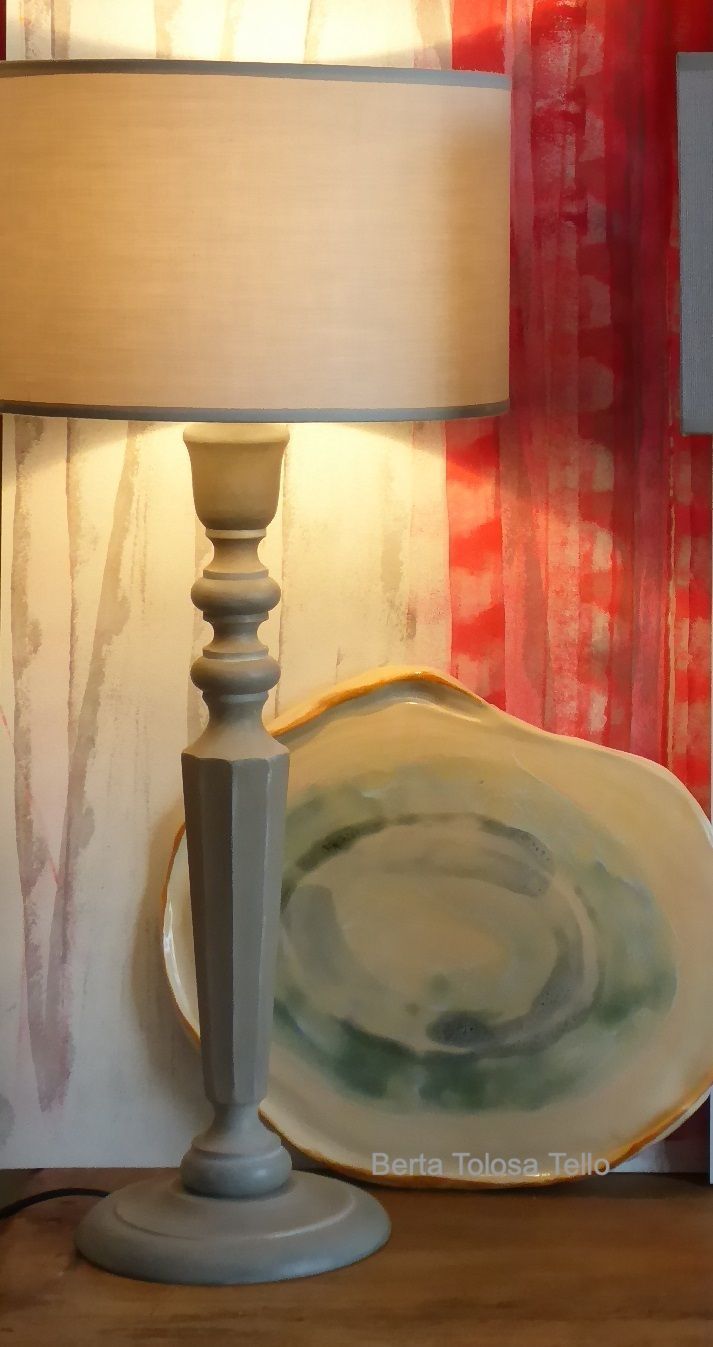 Una lámpara está sobre una mesa al lado de un plato.