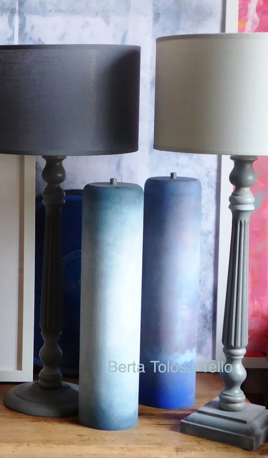 Hay tres velas sobre una mesa al lado de una lámpara.