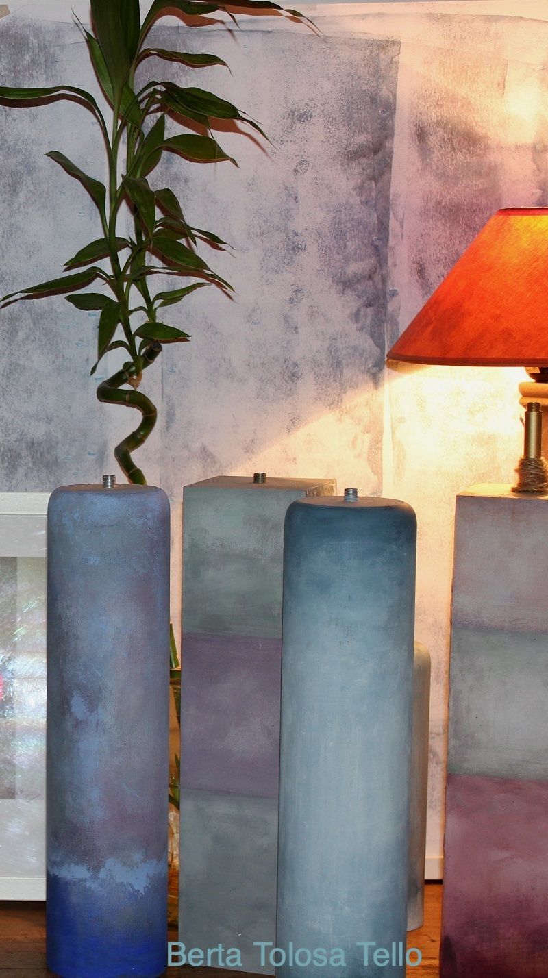 Tres velas están alineadas junto a una lámpara y una planta.