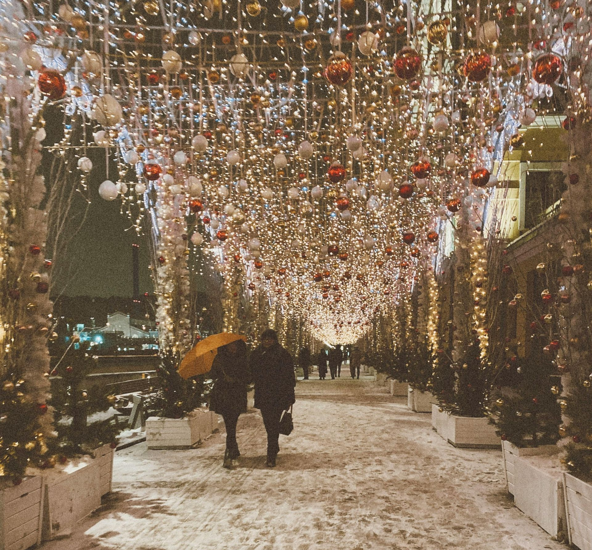 Couple walking under holiday lights & decorations on a snowy sidewalk. HunnyDo's  Blog, Don't hibernate, Hunny