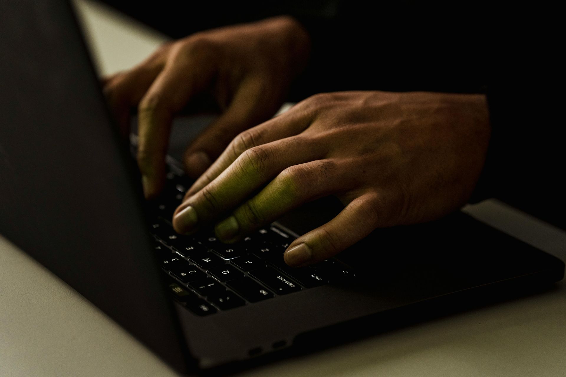 A person is typing on a laptop computer in the dark.