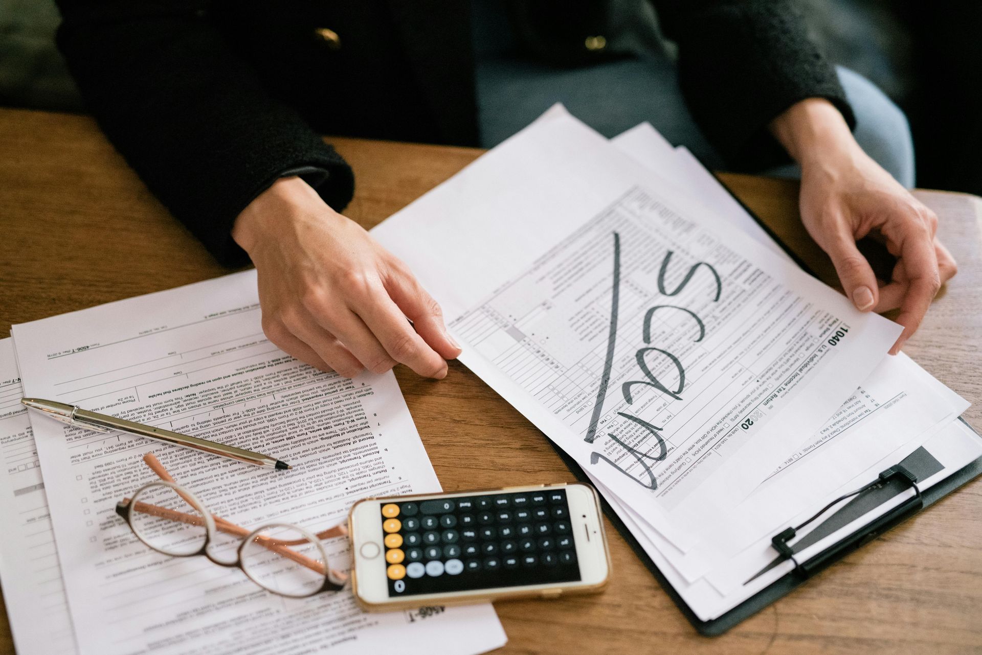 A person is sitting at a table with papers and a cell phone.