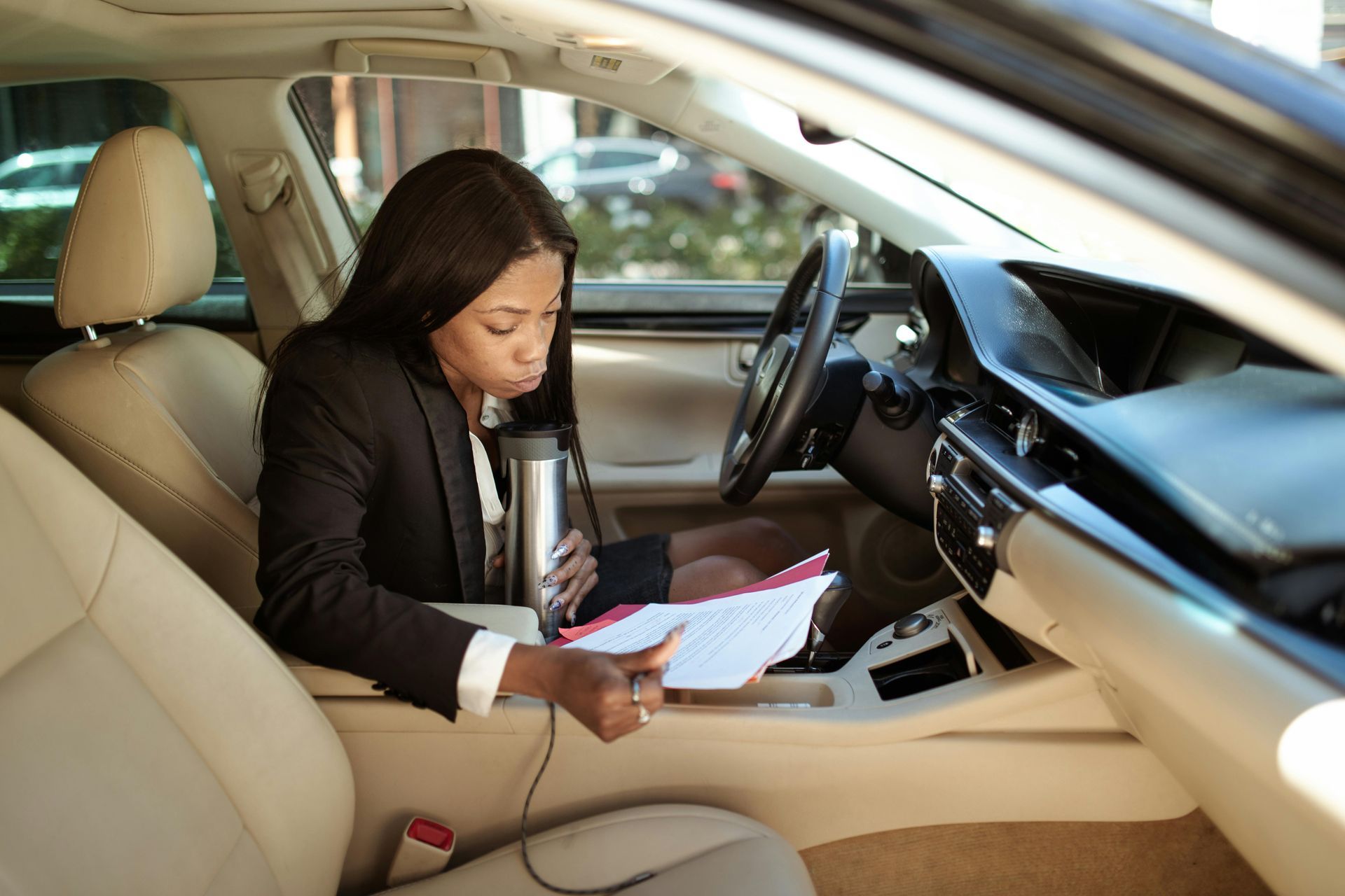 A woman inside her car, examining shipping documents with concern.