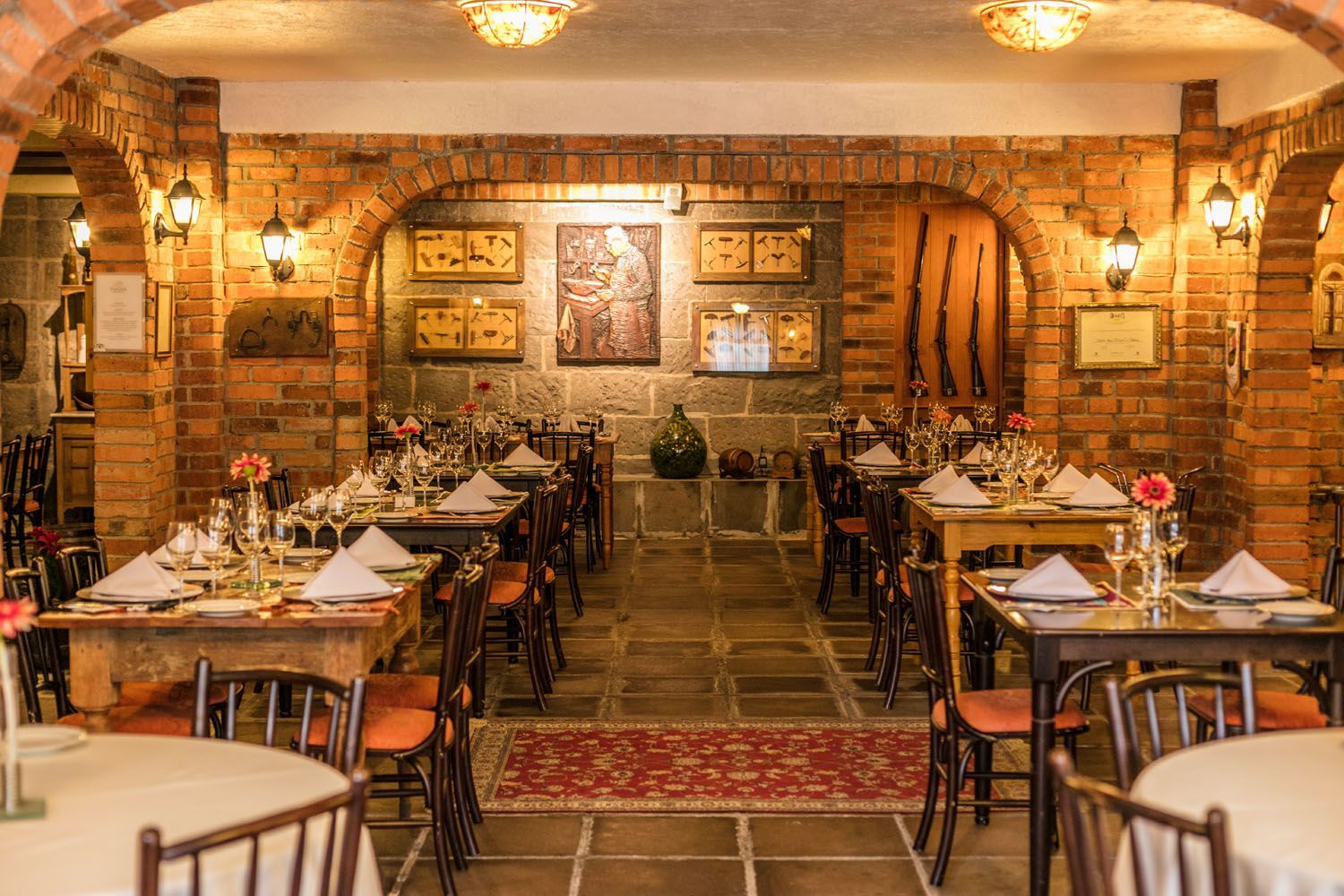 um restaurante cheio de mesas e cadeiras e uma parede de tijolos.
