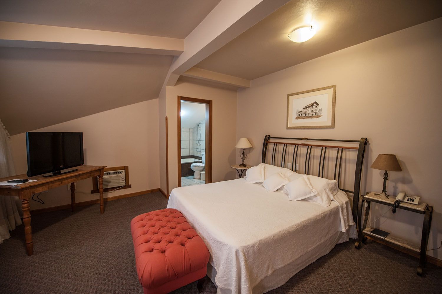 um quarto de hotel com cama king size, mesa, televisão e banco.
