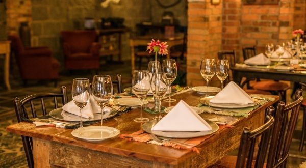 uma mesa de madeira com pratos, guardanapos e taças de vinho em um restaurante.