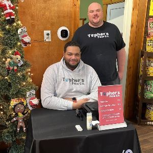 Two men are standing next to each other in front of a christmas tree.