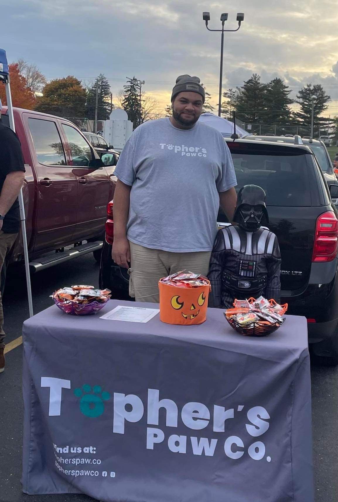 A man is standing in front of a table with a darth vader statue on it.