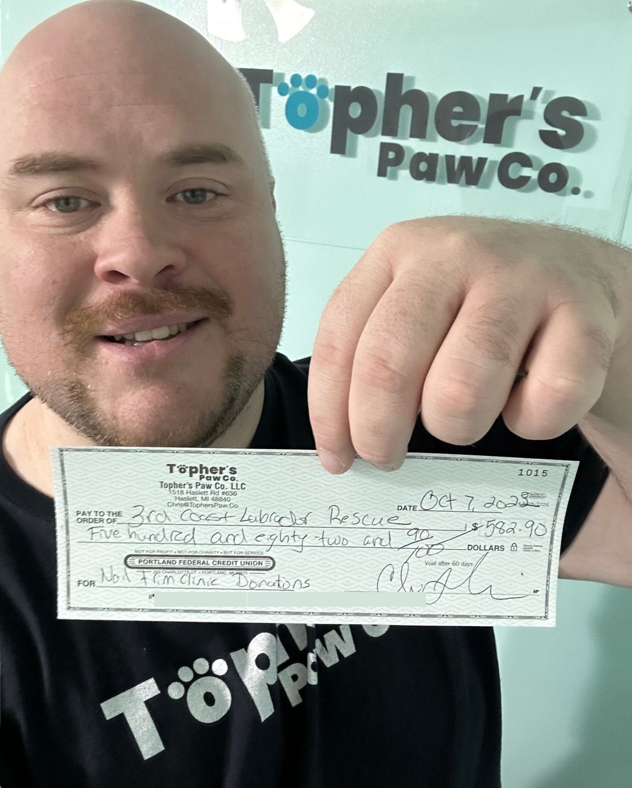 A bald man is holding a check in his hand.