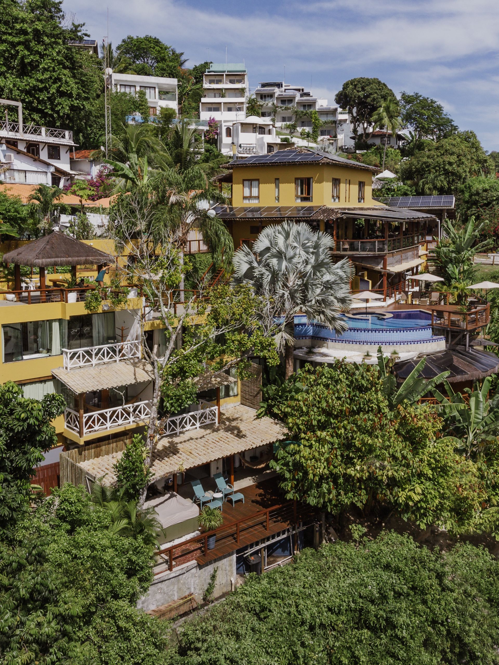 Uma vista aérea de uma piscina com painéis solares no telhado. - Pousada Pasargada