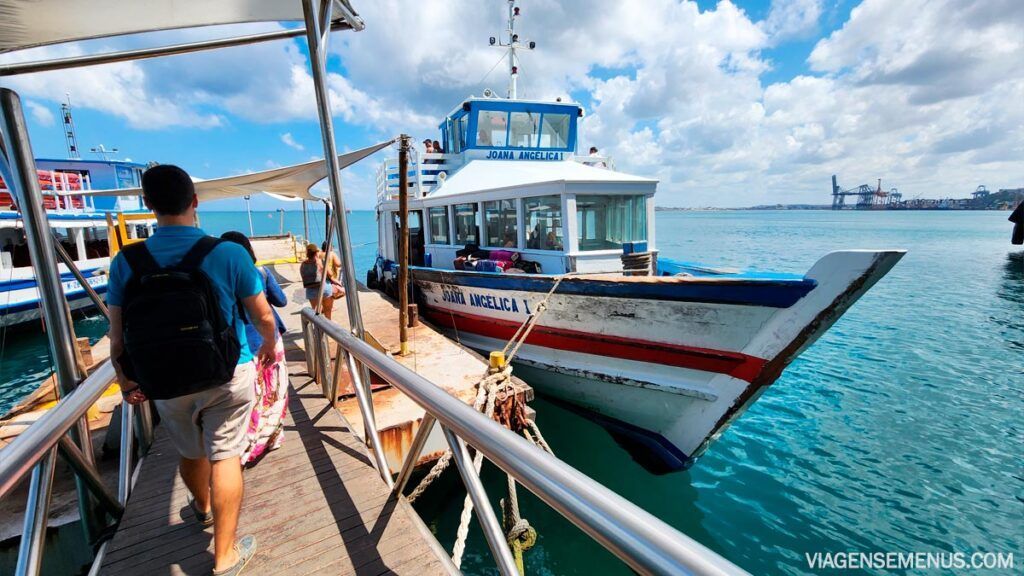 Um homem com uma mochila está caminhando em direção a um barco na água. - Pousada Pasargada