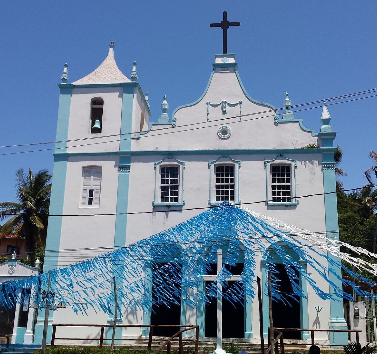 Uma igreja branca e azul com uma cruz no topo - Pousada Pasargada