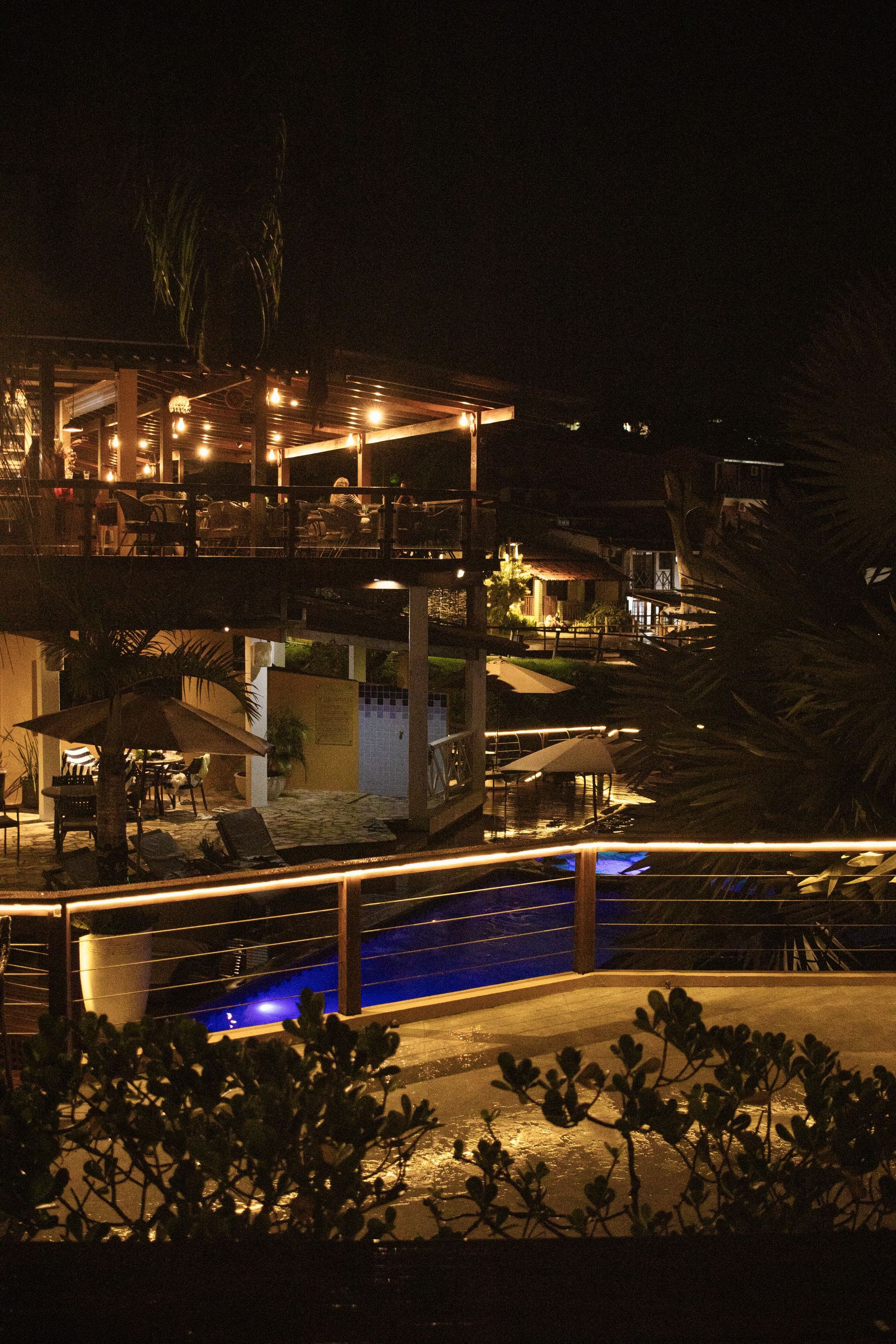 Uma grande piscina é iluminada à noite - Pousada Pasargada