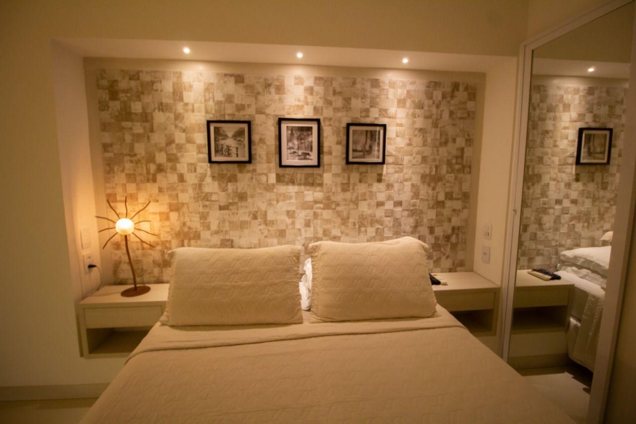 Um quarto com uma cama, mesas de cabeceira, um candeeiro e um espelho. - Pousada Pasargada