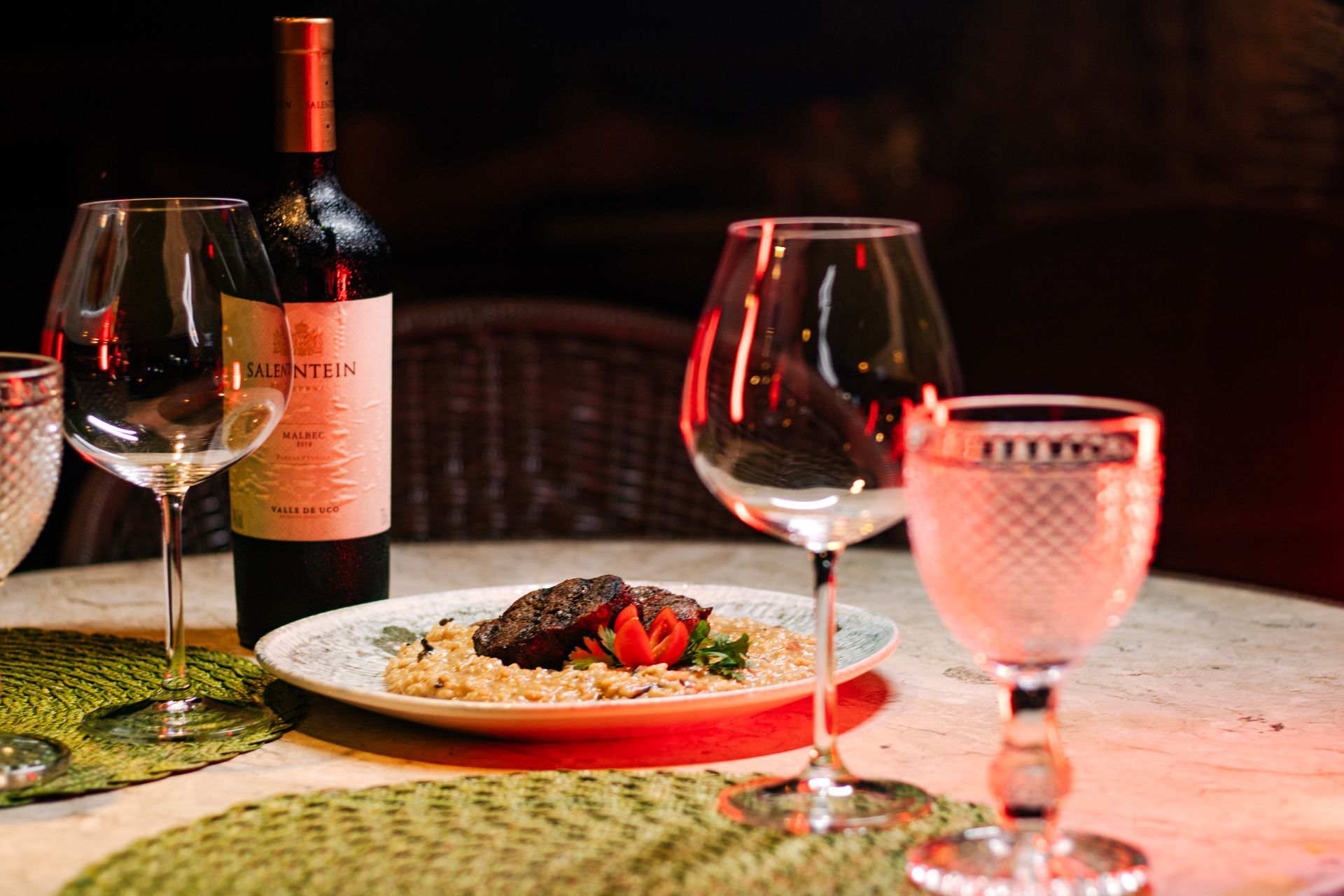 Uma garrafa de vinho, duas taças de vinho e um prato de comida na mesa. - Pousada Pasargada