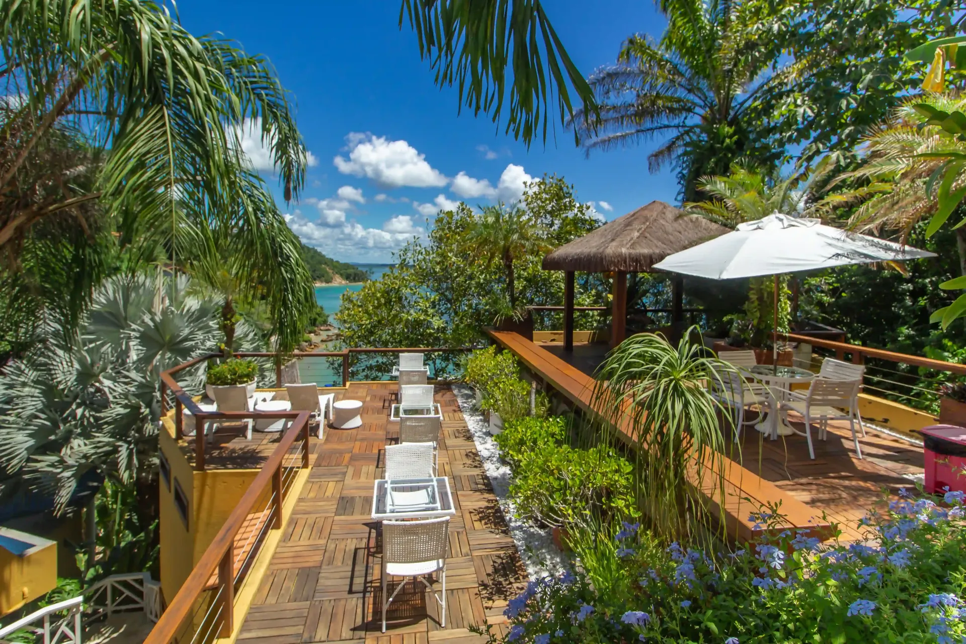Um mirante com mesas e cadeiras com vista para o oceano ao pôr do sol - Pousada Pasargada