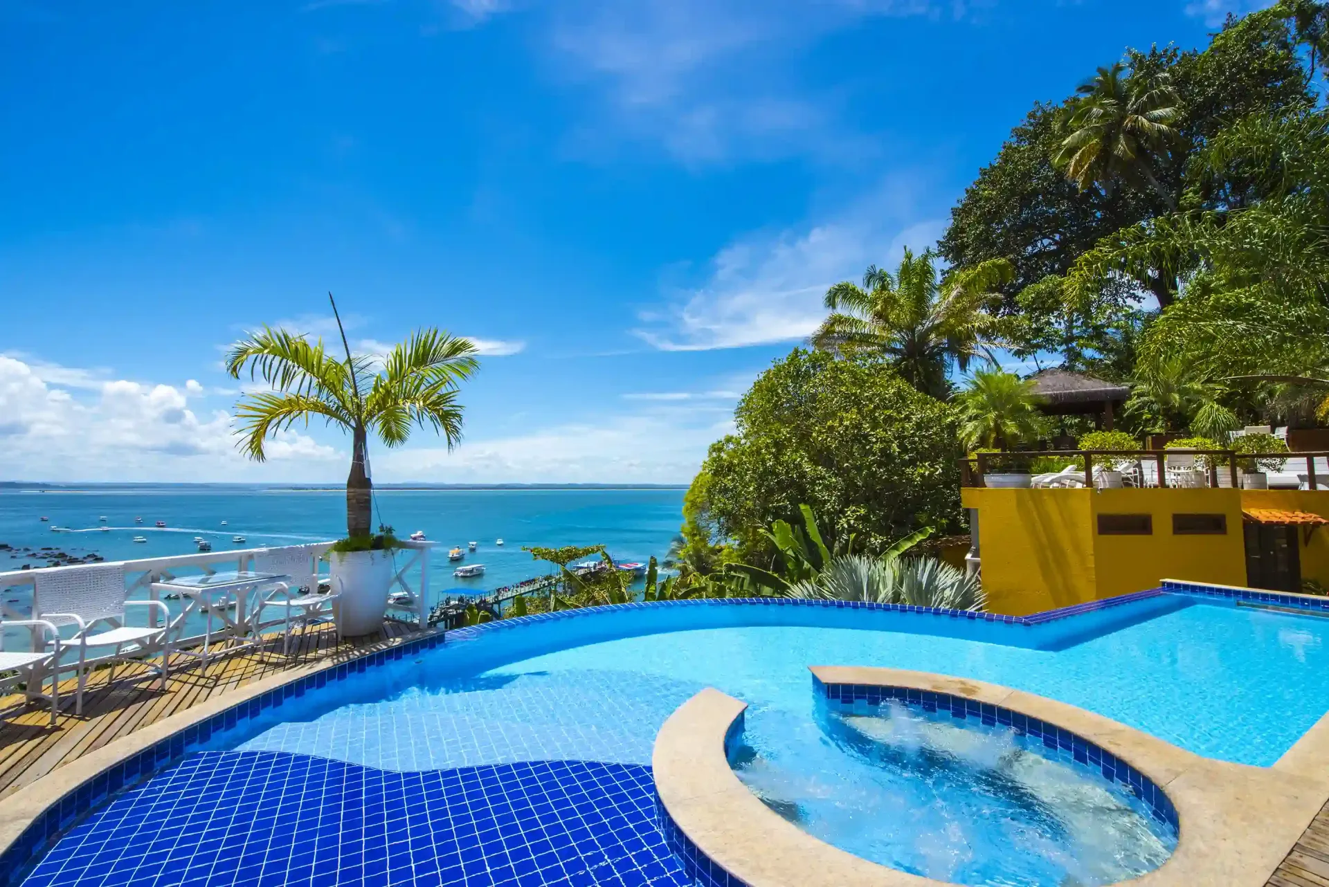 Duas cadeiras estão sobre um deck de madeira com vista para o oceano. - Pousada Pasargada