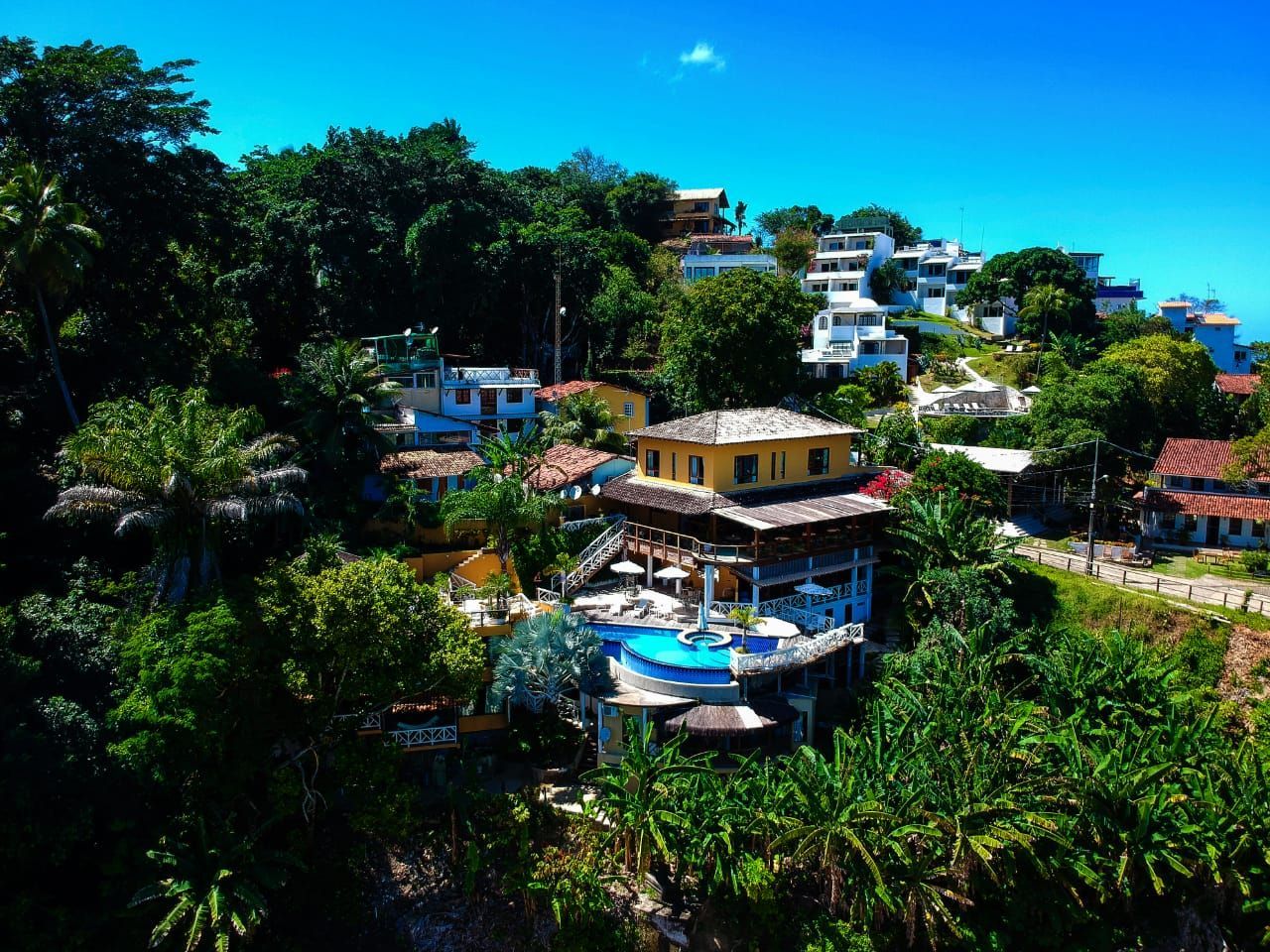 Uma palmeira é silhuetada contra o pôr do sol sobre o oceano. - Pousada Pasargada