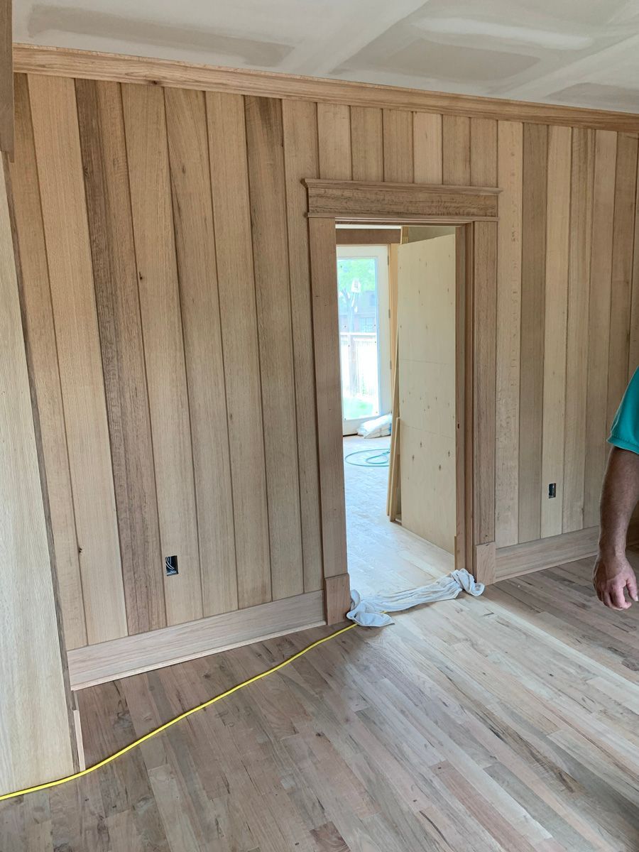 A man is measuring a wooden floor in a room.