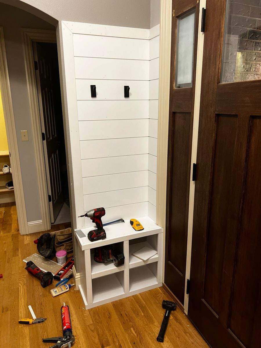 A hallway with a bench and a coat rack being built.