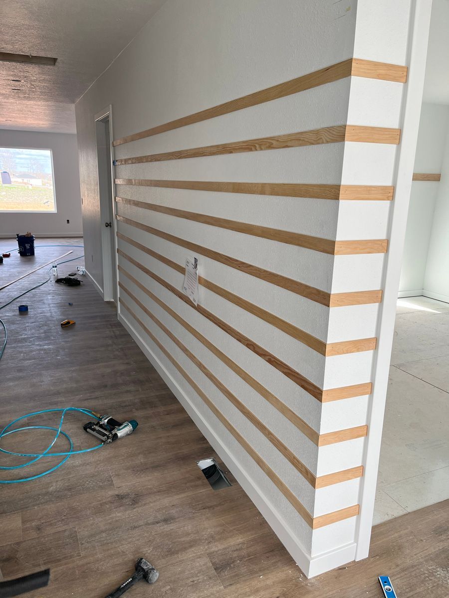 A white wall with wooden stripes on it is being painted.