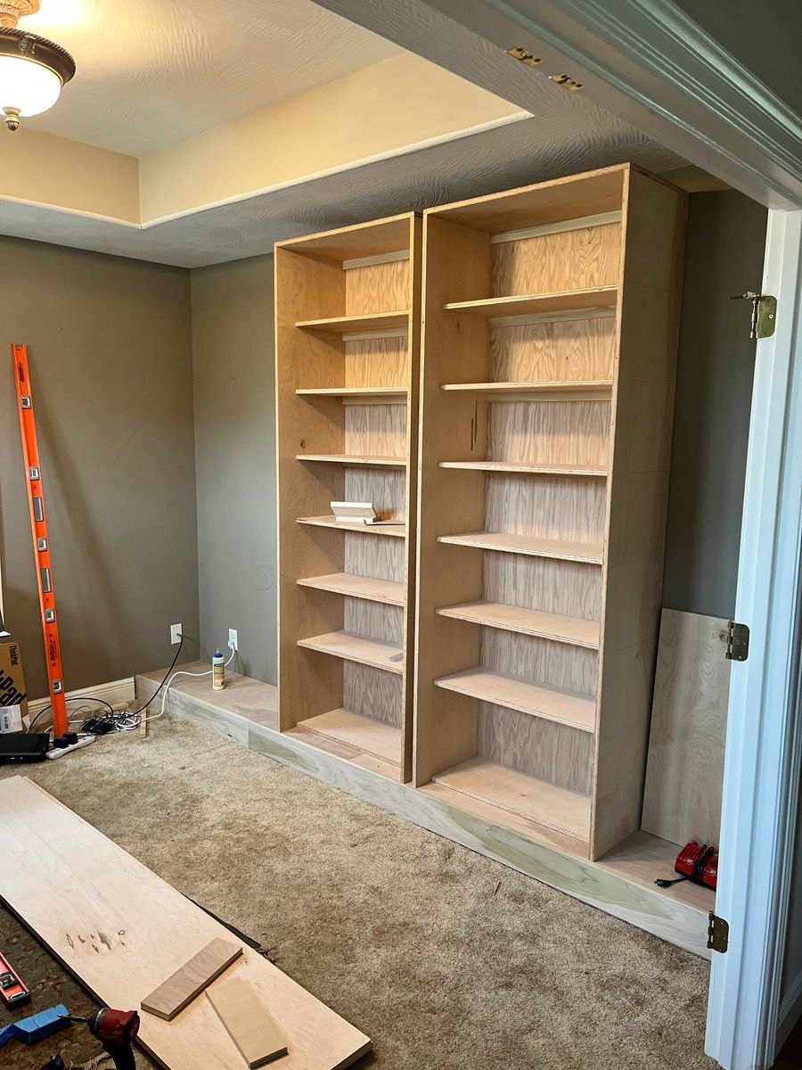 Two wooden shelves are being built in a room.