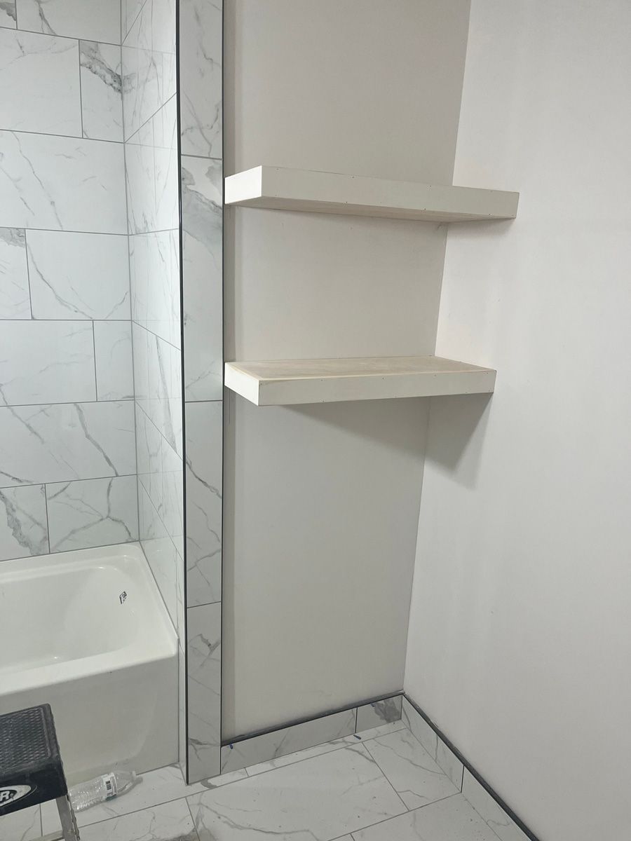 A bathroom with a bathtub and shelves in it.