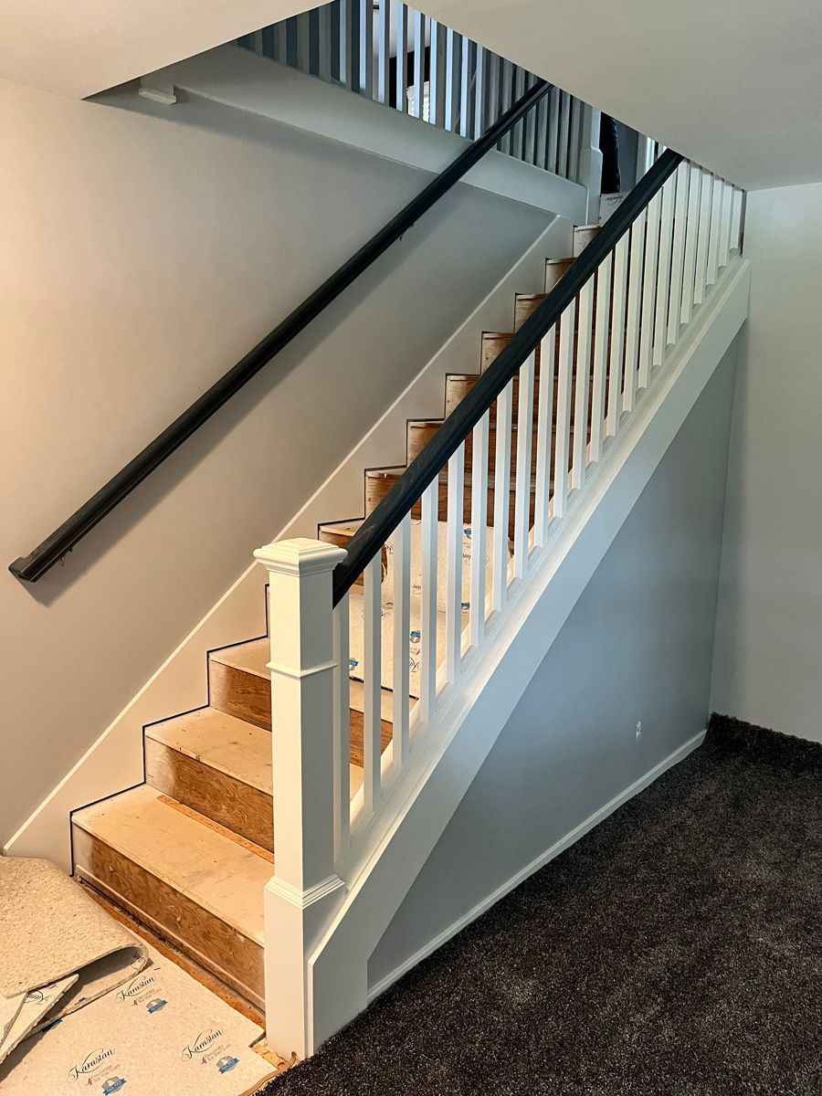 A white staircase with a black railing in a room.