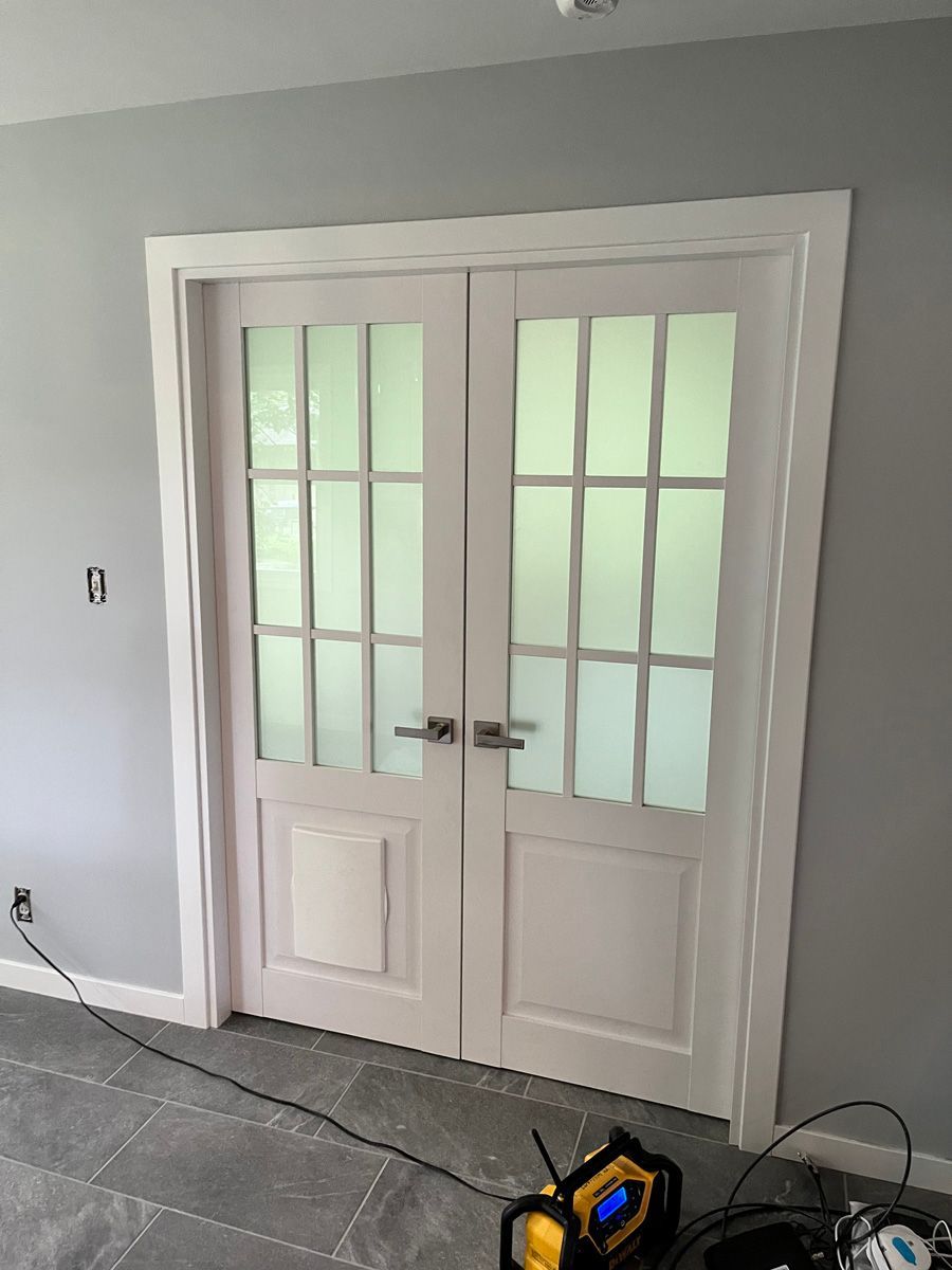 A pair of white french doors with frosted glass in a room.