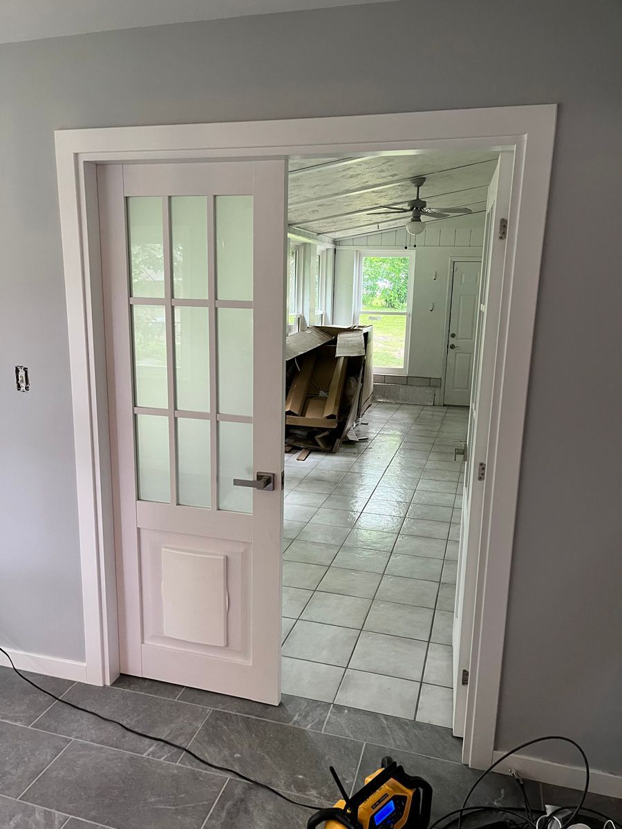 A white door is open to a room with tile floors.