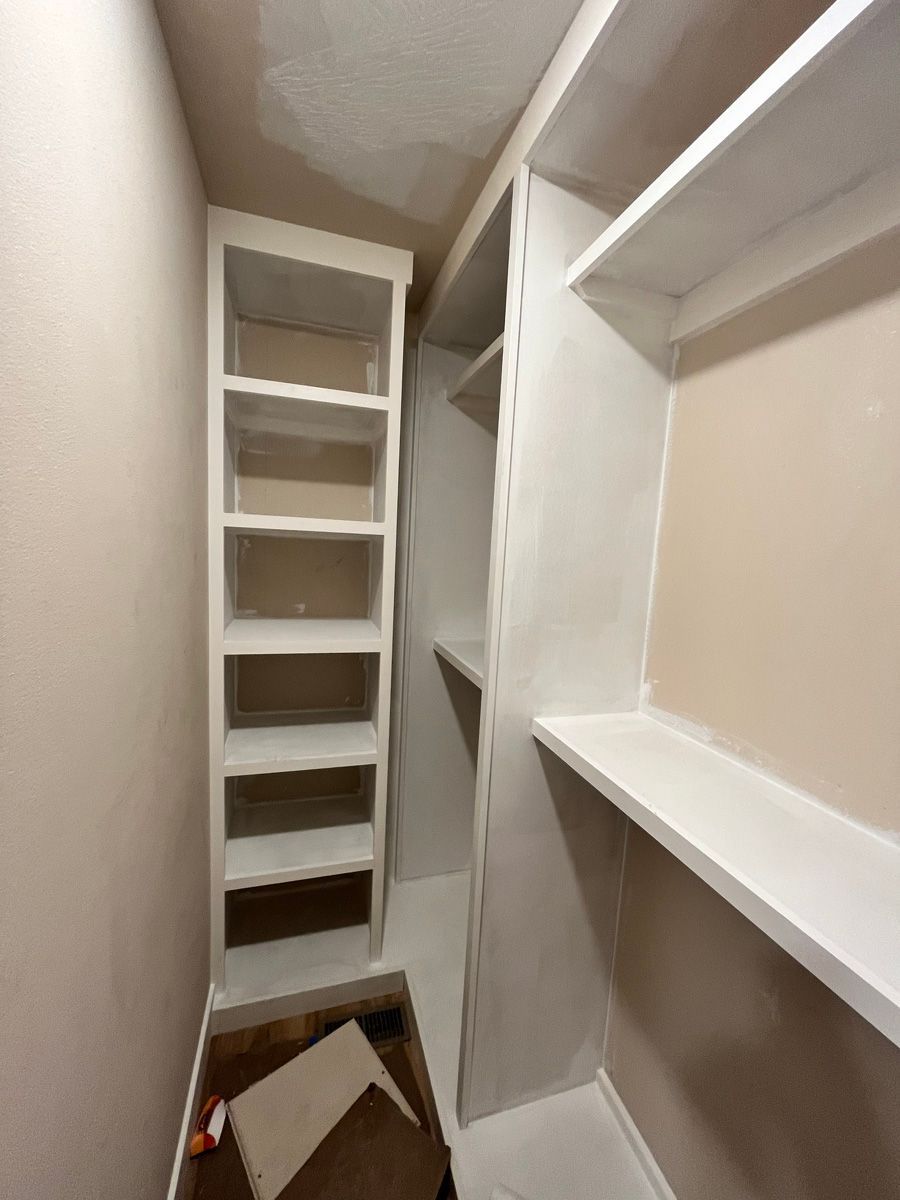 A walk in closet with lots of shelves and a box on the floor.