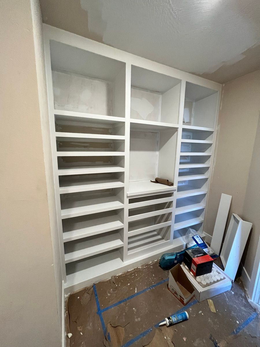 A room with a lot of shelves and a bottle of glue on the floor.