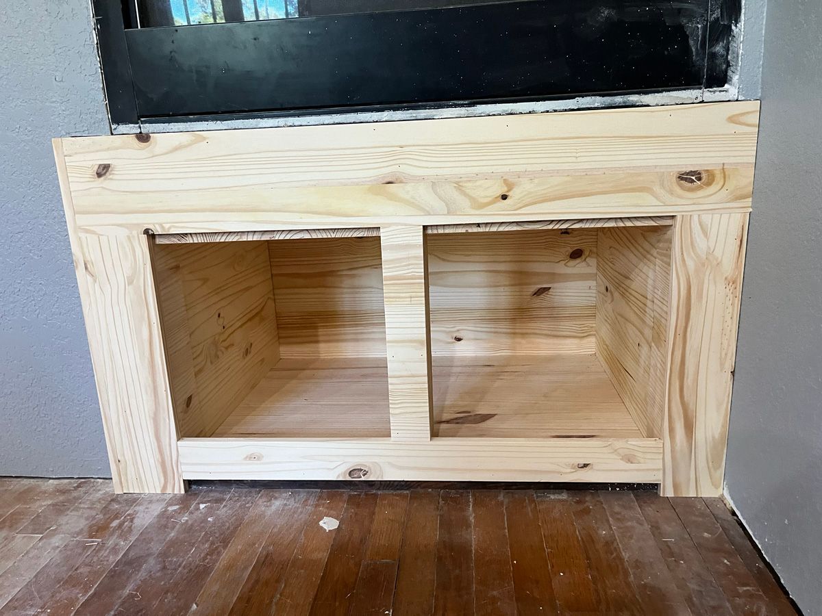 A wooden cabinet is being built in a corner of a room.