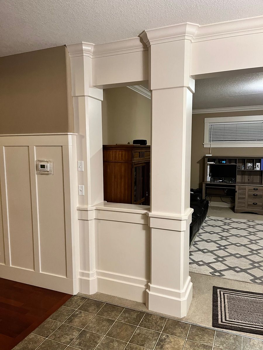 A living room with a pillar between the living room and dining room.