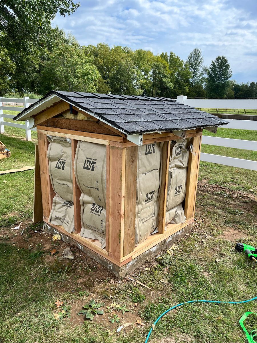 A small wooden shed is being built in the grass.