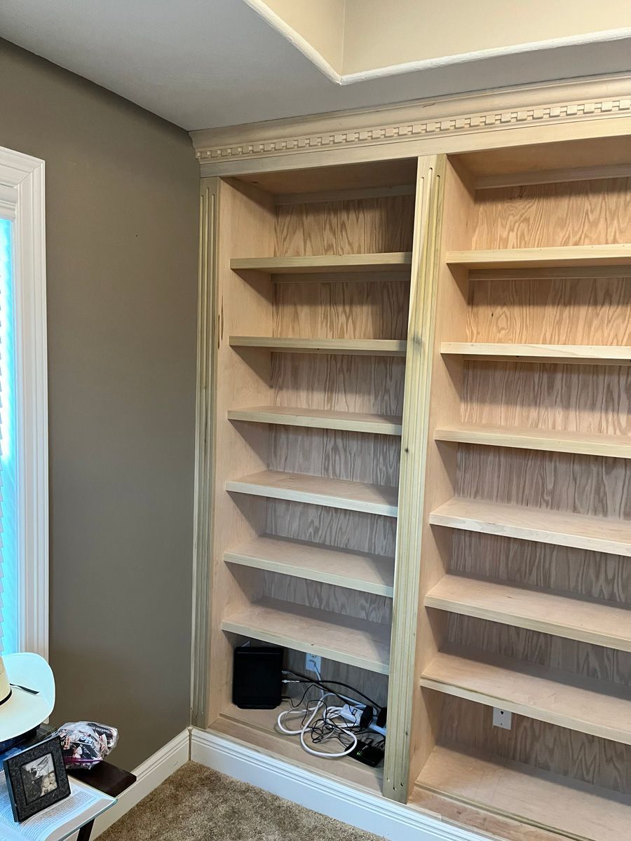 A room with a lot of shelves and a window.