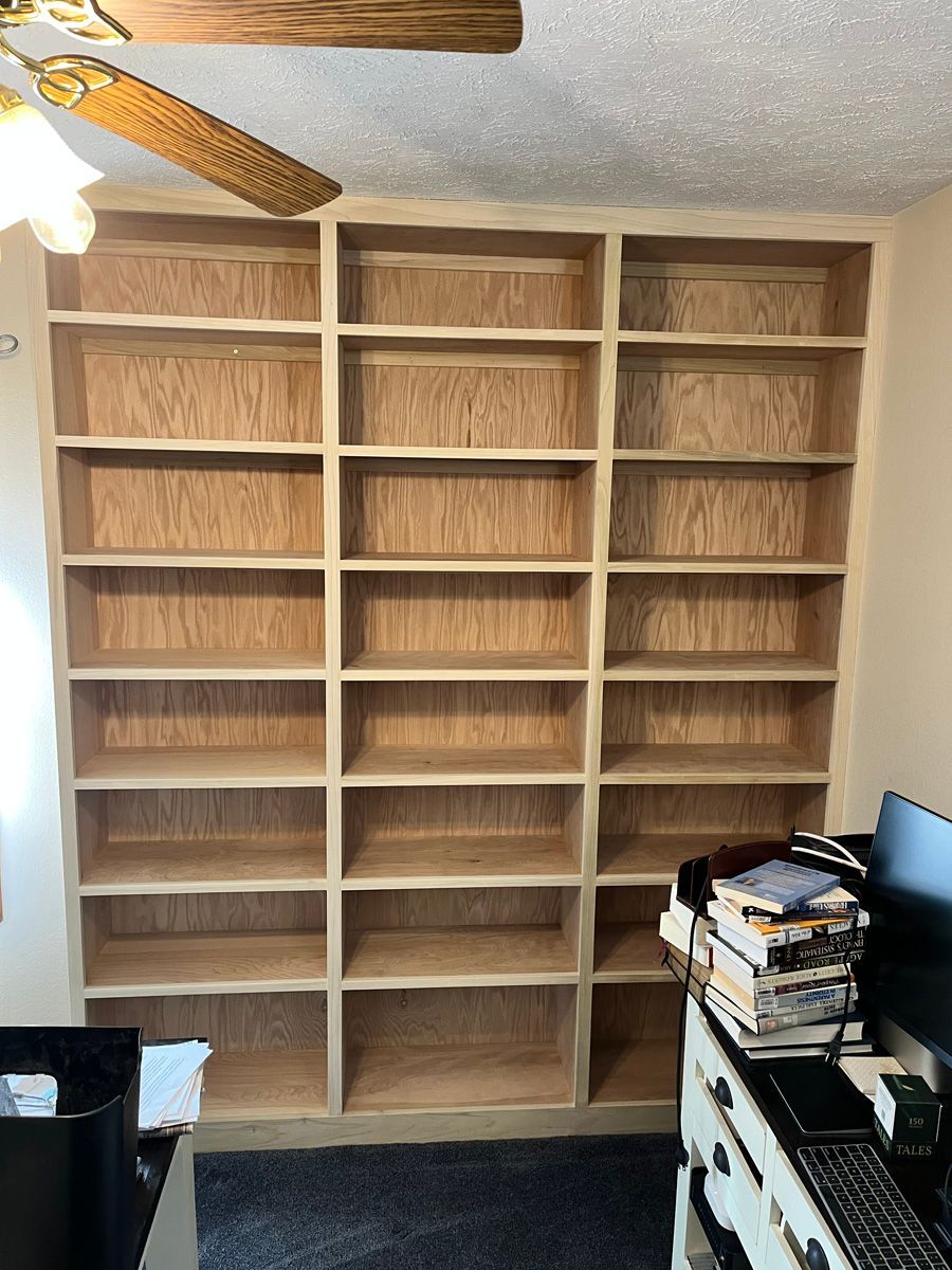 A room with a lot of shelves and a ceiling fan