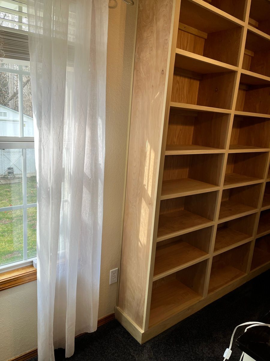 A room with a lot of shelves and a window.