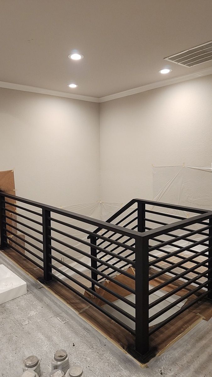 A metal railing is being installed on a staircase in a room.