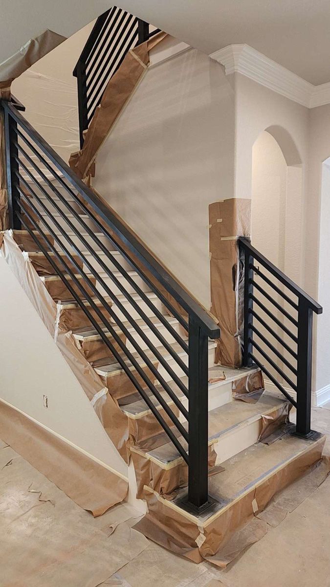 A staircase with a black railing is being built in a house.