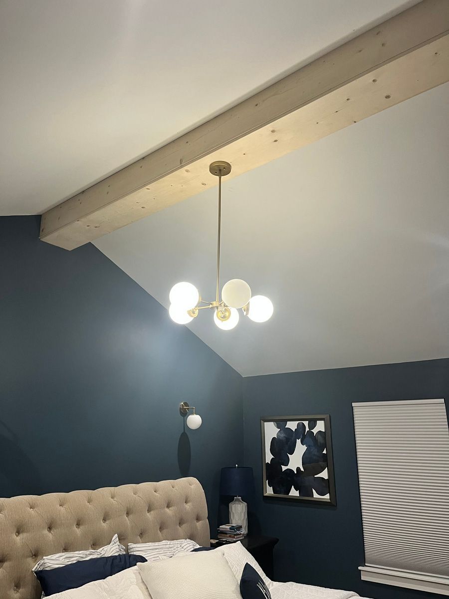 A bedroom with a bed and a chandelier hanging from the ceiling.