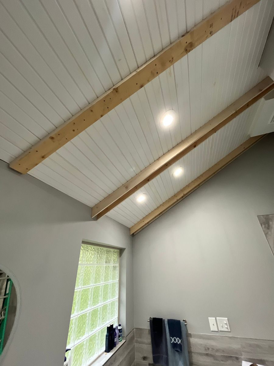A bathroom with a vaulted ceiling and wooden beams.