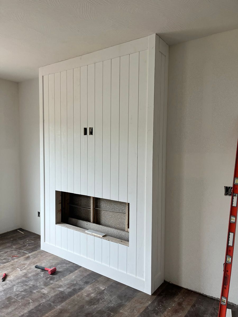 A living room with a fireplace and a ladder in the corner.