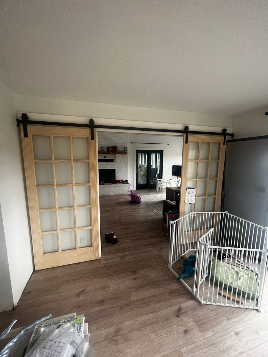 A living room with sliding barn doors and a crib.