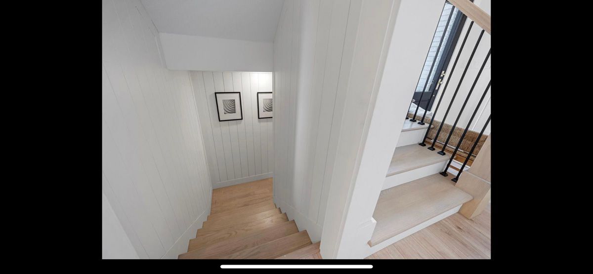 A picture of a hallway and stairs in a house.